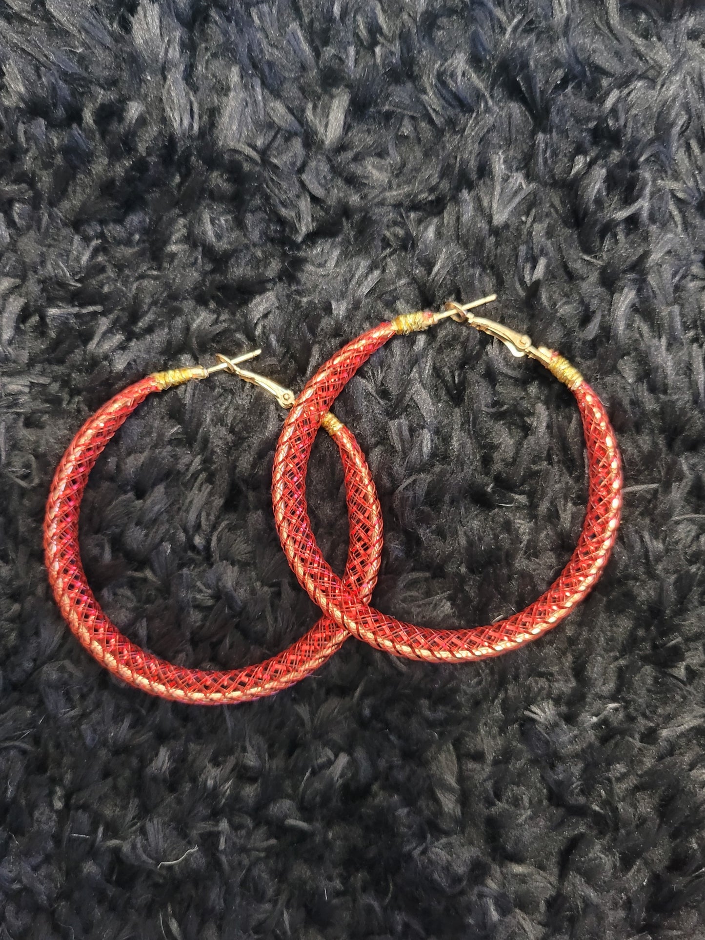 Red lace hoop earrings on a textured black surface