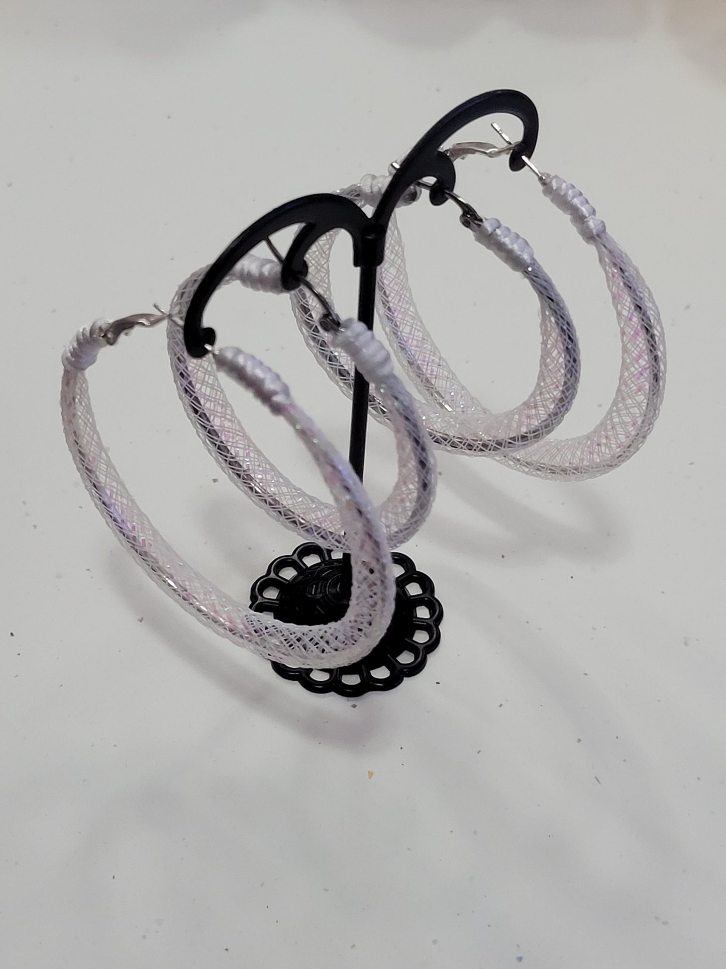 White lace silver earring with black reel on a white background