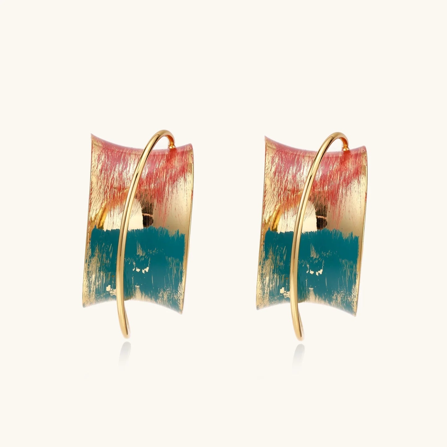 Gold-plated hoop earrings with teal and coral enamel brushstroke design on cream background