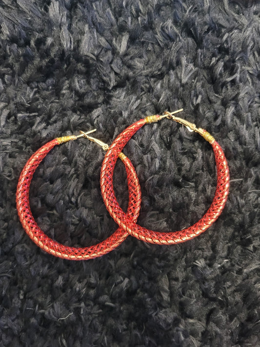 Red lace hoop earrings on a textured black surface