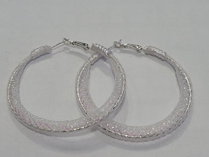 Pair of white lace hoop earrings with glittery finish on a gray background