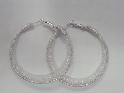 Pair of white lace and silver hoop earrings on a light gray background