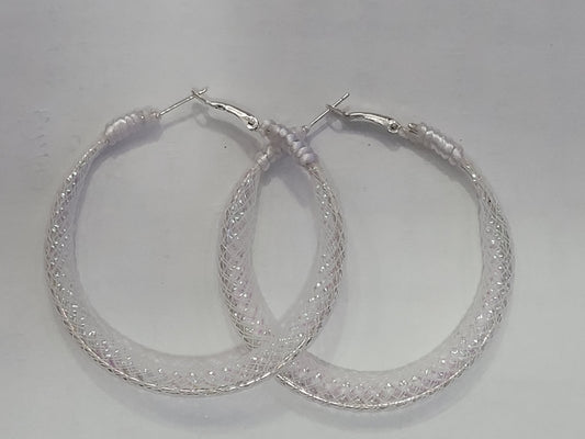 Pair of white lace and silver hoop earrings on a light gray background