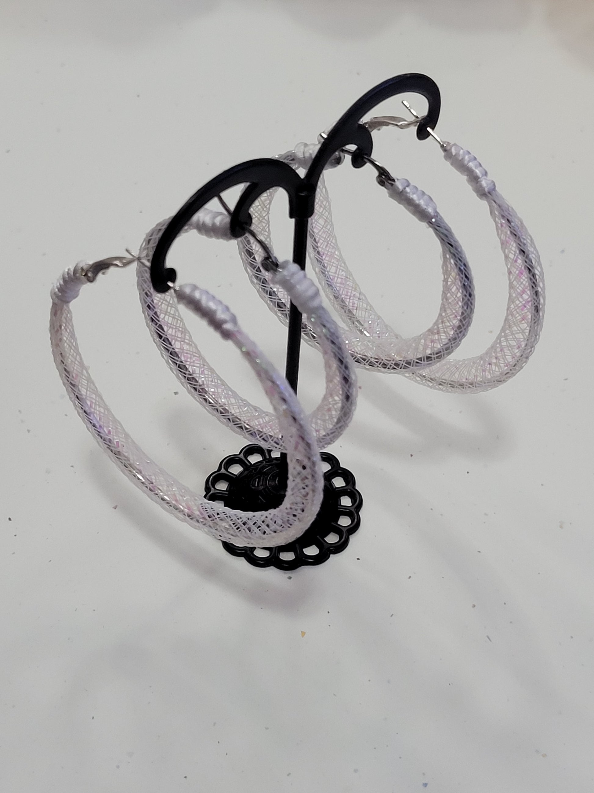 White lace silver earring with black reel on a white background